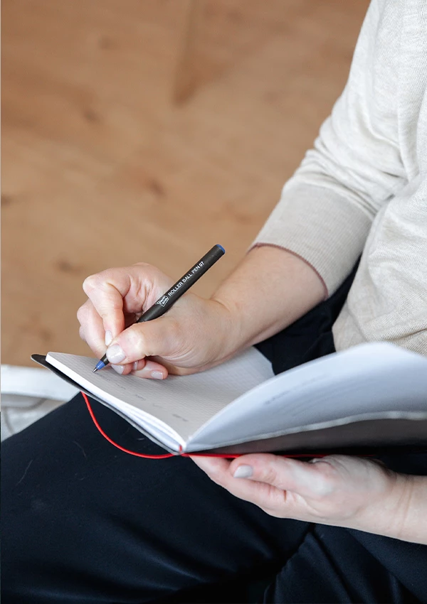 Therapeutin notiert sich Gesprächsinhalte mit einem Stift in einem Notizbuch